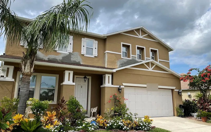 The area re-stuccoed in fresh coats, visible as gray patches against the tan house color, Central Florida example