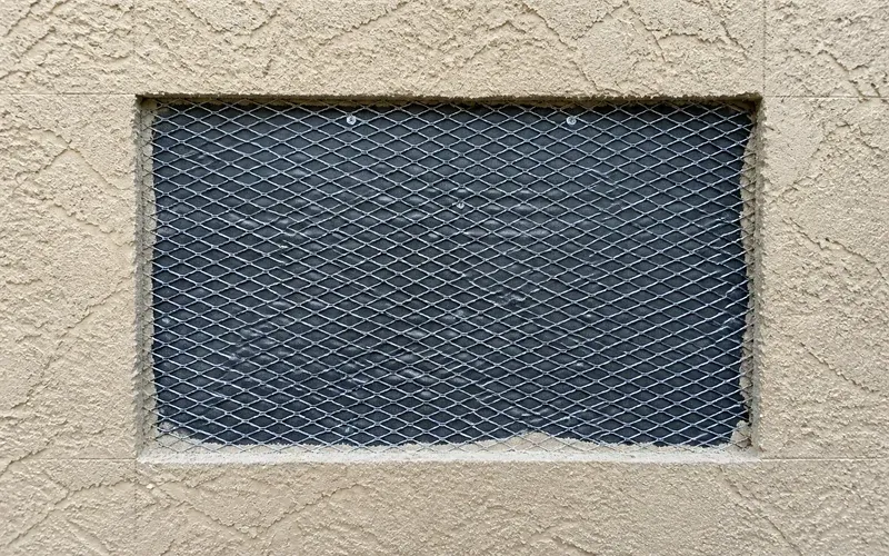 A rectangular section of stucco removed down to the metal lath, showing the extent of an opened wall