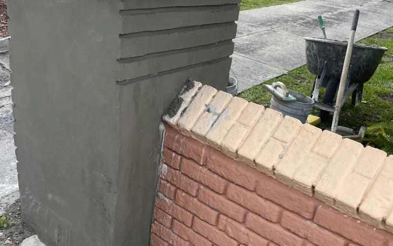 Brick coursing being hand-tooled into the wet stucco, a level and tools resting on the column, Central Florida example