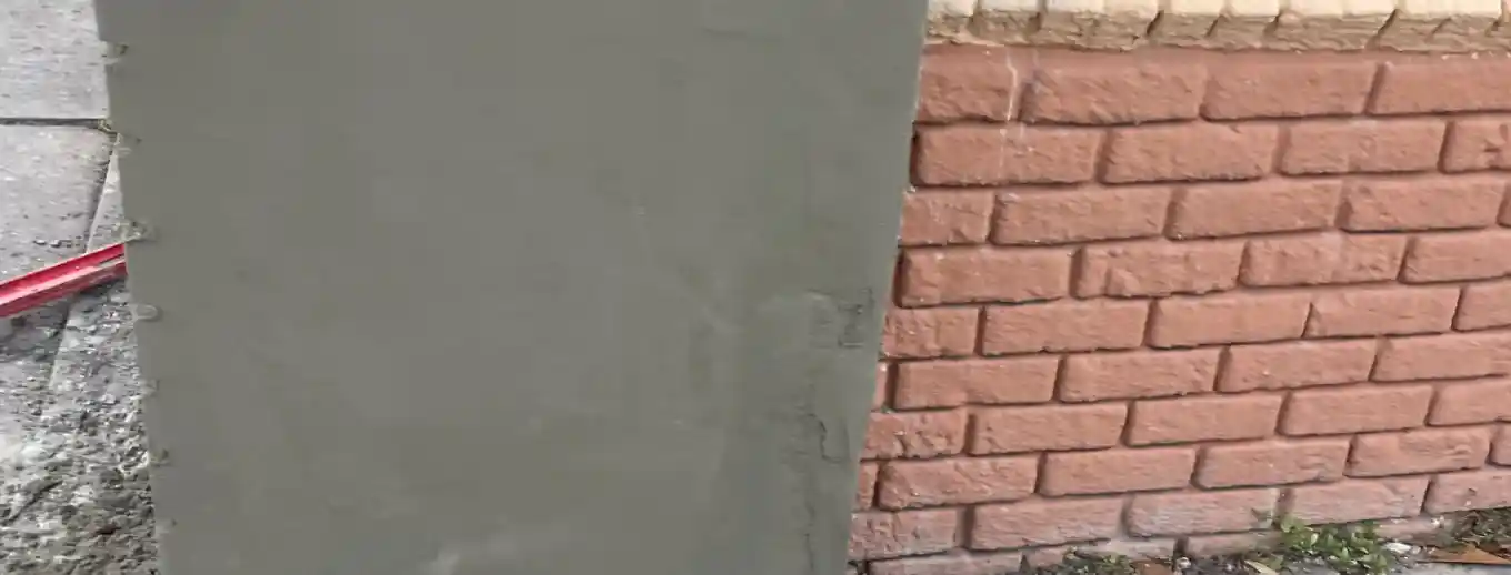 A rebuilt entry column in plain smooth stucco beside a brick wall, Central Florida example