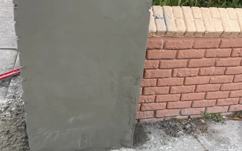 A rebuilt entry column in plain smooth stucco beside a brick wall, Central Florida example