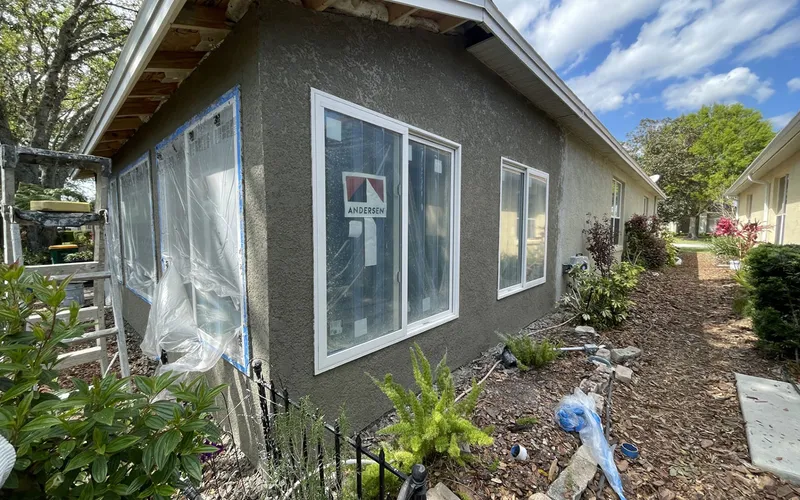 Wider view of the house with several new windows installed and unfinished stucco bands around each opening, Central Florida example