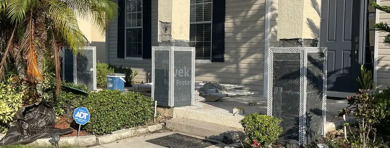 Stucco columns and a low wall at the entrance to a driveway, mid-repair, Central Florida example