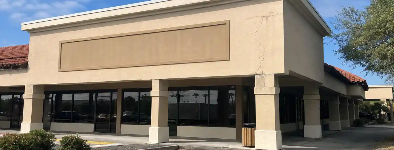 A commercial storefront with stucco cracking near a column